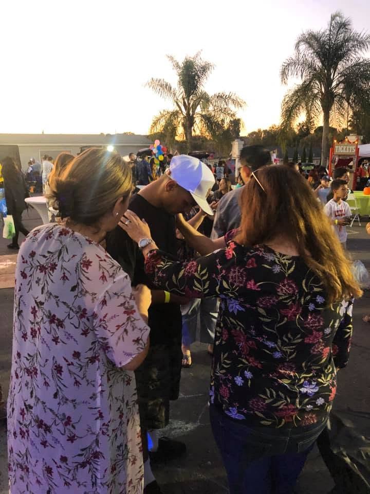 Maria praying over someone at an outdoor gathering